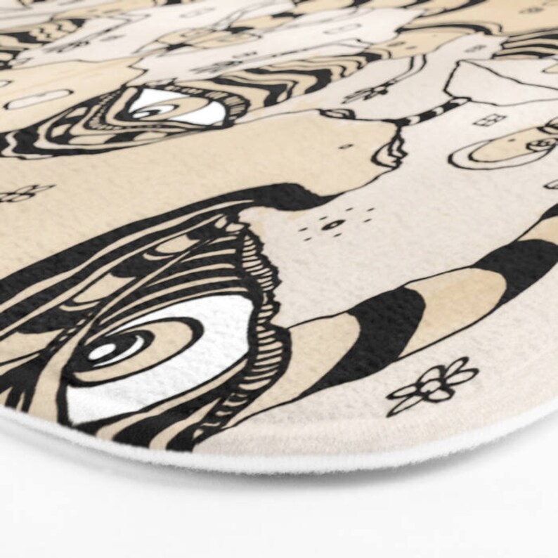 May include: A beige and black patterned bath mat with a large eye design. The eye is surrounded by intricate black lines and swirls.