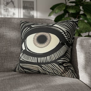 May include: Black and white throw pillow with a large eye graphic. The eye is white with a black pupil and a detailed design around it.