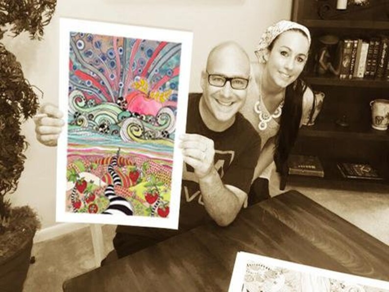 May include: A couple holding a colorful, whimsical art print featuring a swirling, abstract design with a pink heart and a black and white path leading to a field of strawberries.