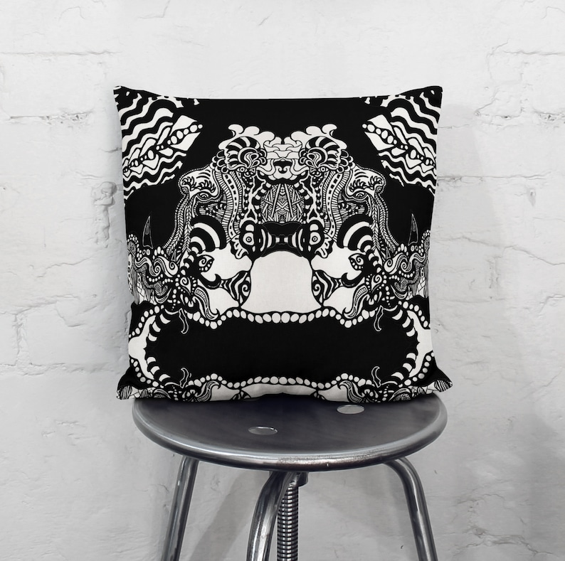 May include: Black and white throw pillow with a detailed, intricate design featuring a symmetrical pattern of swirling lines and shapes.