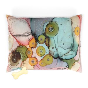 May include: A colorful dog bed with a whimsical abstract design featuring swirling shapes, eyes, and dots in shades of pink, blue, green, and yellow. A white bone is in the foreground.