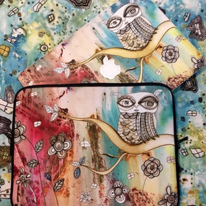 May include: Two laptop skins with an owl design. The top skin is a light blue background with a white owl on a branch. The bottom skin is a multi-colored background with a brown owl on a branch. Both skins feature a watercolor style with floral accents.