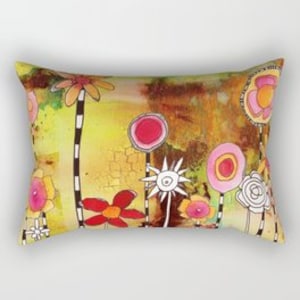 May include: A colorful pillow with a whimsical design featuring stylized flowers in shades of pink, yellow, red, and white on a brown and yellow background.