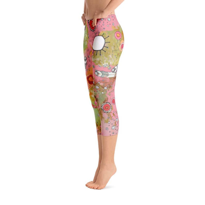 May include: Pink and green capri leggings with a colourful abstract pattern featuring flowers, circles, and lines. The leggings are made of a stretchy, comfortable fabric.