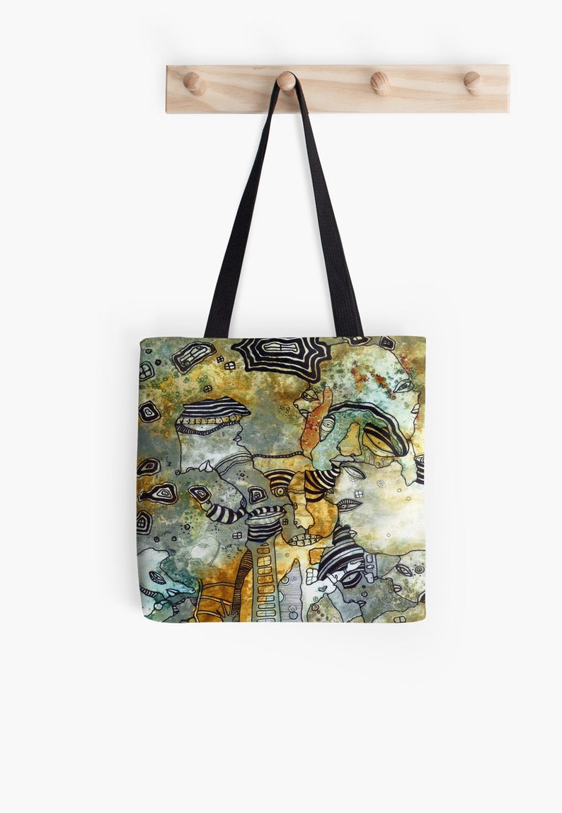 May include: A tote bag with a colorful abstract design featuring a variety of shapes and patterns in shades of brown, green, and blue. The design appears to be hand-drawn and includes stylized faces and geometric shapes.