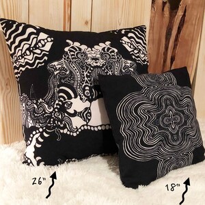 May include: Two black and white patterned throw pillows. The larger pillow is 26 inches and features a complex, abstract design. The smaller pillow is 18 inches and features a circular, concentric pattern.