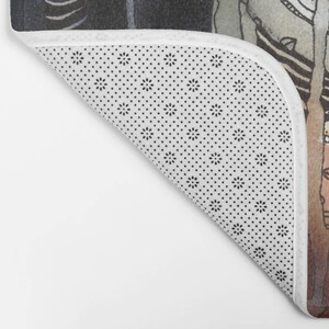 May include: A white bath mat with a black and white polka dot pattern. The mat is folded in half and the edge is visible.
