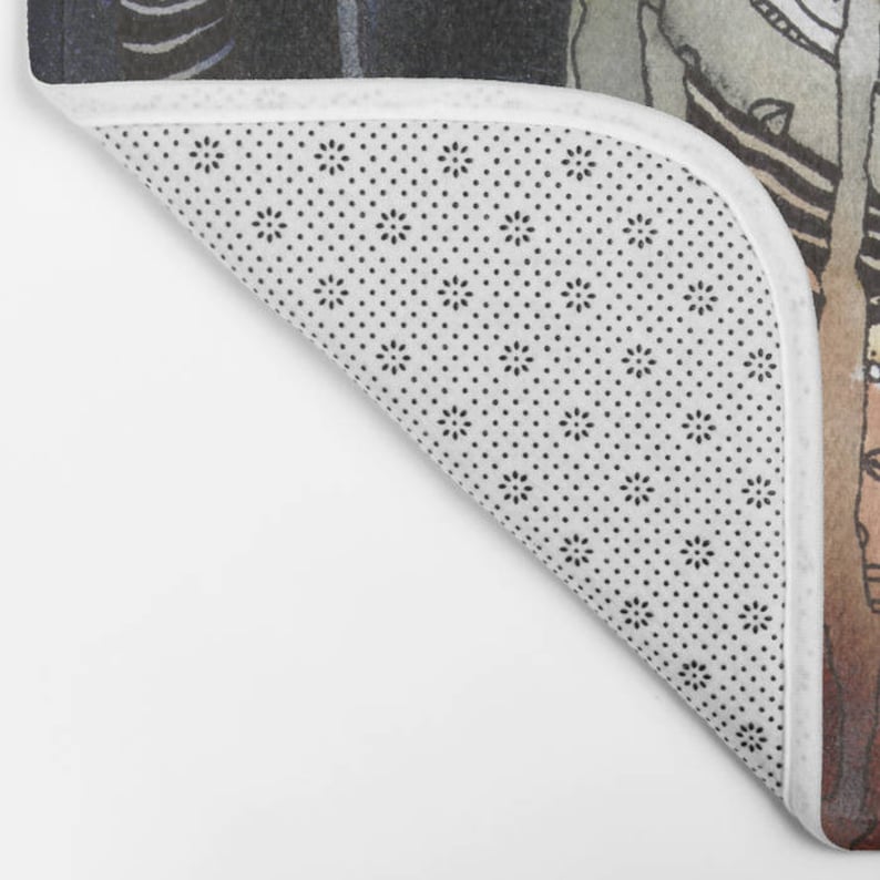 May include: A white bath mat with a black and white polka dot pattern. The mat is folded in half and the edge is visible.