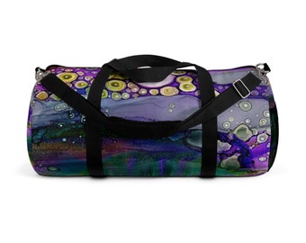 Puede incluir: Una bolsa de lona negra con un diseño abstracto morado, verde y amarillo. El diseño presenta círculos y remolinos.