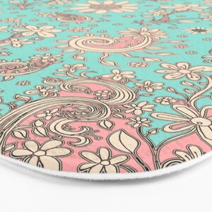 May include: A teal and pink patterned bath mat with a floral design. The pattern features swirls, leaves, and flowers.