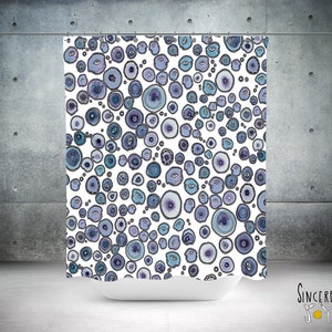 May include: A white shower curtain with a pattern of blue and purple circles. The circles have a variety of sizes and shapes, and some have a white outline.