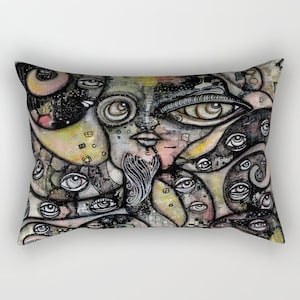 May include: A colorful pillow with a surreal, abstract design featuring a face with multiple eyes and a beard. The background is a mix of black, white, and gray with hints of yellow and green.