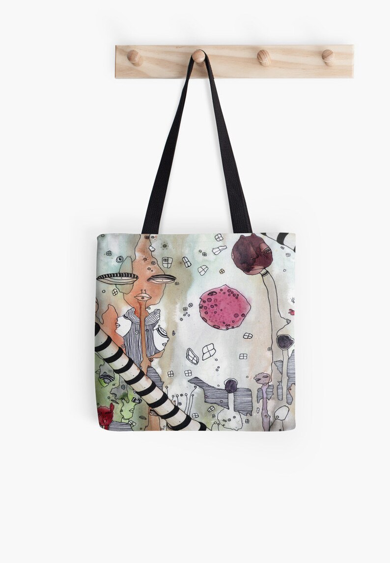 May include: A tote bag with a colorful abstract design featuring a pink circle, black and white stripes, and a variety of shapes and lines.