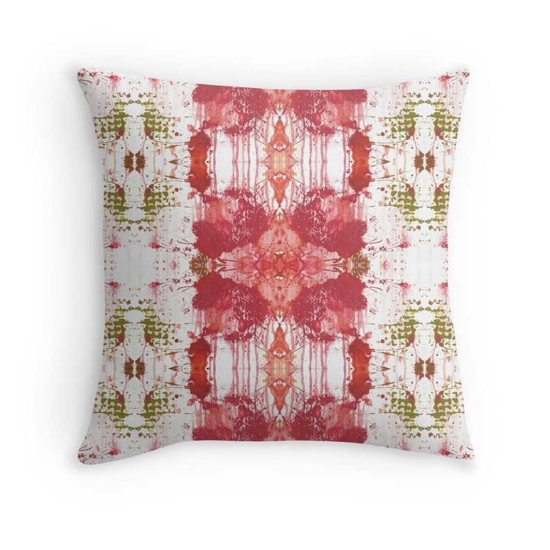 May include: Red and green abstract pattern on a white background. The pattern is symmetrical and has a geometric design. The pillow is a square shape.