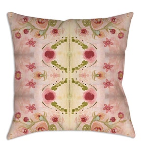 K&ouml;nnte beinhalten: Quadratisches Zierkissen mit floralem Aquarelldesign. Das Kissen zeigt ein symmetrisches Muster aus rosa Rosen, kleinen rosa Bl&uuml;ten und gr&uuml;nem Laub auf einem hellrosa und cremefarbenen Hintergrund.