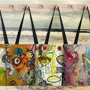 Peut inclure: Sept sacs fourre-tout color&eacute;s avec des &oelig;uvres d'art originales sont accroch&eacute;s &agrave; un support en bois sur fond de plage. Les sacs pr&eacute;sentent des motifs abstraits et une vari&eacute;t&eacute; de couleurs, notamment le bleu, le vert, le jaune, l'orange, le rouge et le violet. Le texte "TOTABLE ART" est affich&eacute; en lettres jaunes sur fond blanc, avec les mots "ORIGINAL ART BY CRISTINE CAMBRER" en dessous.