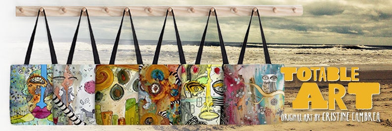 Peut inclure: Sept sacs fourre-tout color&eacute;s avec des &oelig;uvres d'art originales sont accroch&eacute;s &agrave; un support en bois sur fond de plage. Les sacs pr&eacute;sentent des motifs abstraits et une vari&eacute;t&eacute; de couleurs, notamment le bleu, le vert, le jaune, l'orange, le rouge et le violet. Le texte "TOTABLE ART" est affich&eacute; en lettres jaunes sur fond blanc, avec les mots "ORIGINAL ART BY CRISTINE CAMBRER" en dessous.