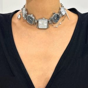May include: A silver necklace with multiple watch faces attached. The necklace has a small star charm hanging from it.