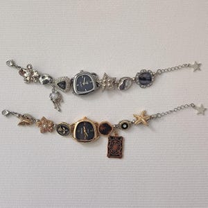 Puede incluir: Dos pulseras de plata y oro con relojes de esfera negra. Los abalorios incluyen estrellas, conchas y flores.