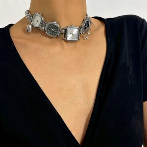May include: A silver choker necklace with multiple square watch faces and a star charm.