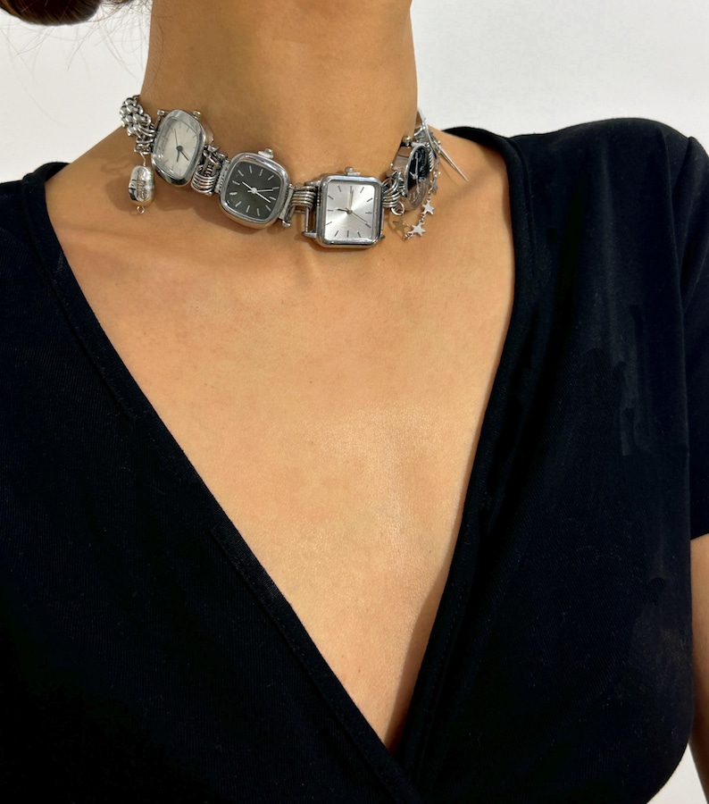 May include: A silver choker necklace with multiple square watch faces and a star charm.