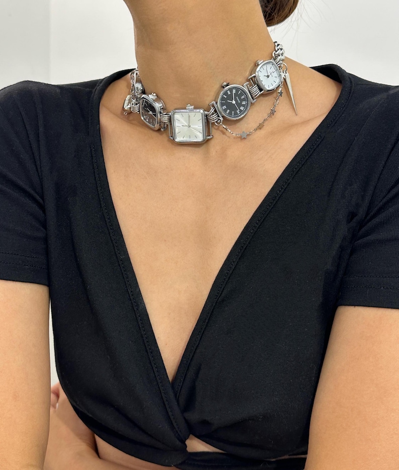 May include: A silver choker necklace with multiple small watch faces attached. The necklace is made of metal and has a delicate chain design.