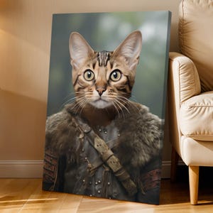 May include: A canvas print featuring a regal cat portrait. The cat, with striking brown and tan markings, is depicted wearing medieval-style armor and a fur-lined cloak. The background is a soft, blurred green, enhancing the portrait's focus.