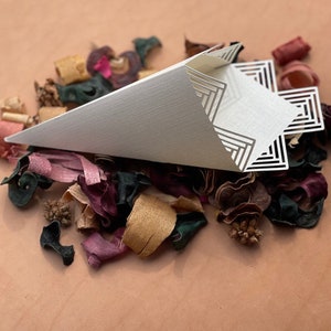 May include: White paper cone with a geometric design, filled with colorful potpourri.
