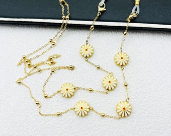 May include: A gold chain with white daisy charms and clear silicone ends. The chain is designed to hold glasses.