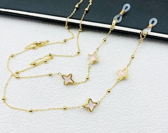 May include: Gold chain with four pink and white flower charms. The chain has small gold beads and is designed to hold glasses.