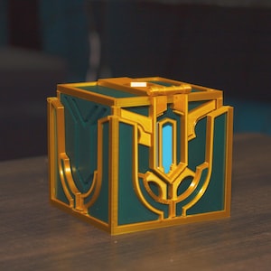 May include: A small, green and gold treasure chest with intricate details. The chest has a hinged lid and a decorative design.