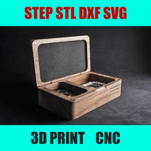 Pode incluir: Uma caixa de madeira com tampa articulada, dividida em dois compartimentos. A caixa está aberta, revelando um pequeno anel e um colar de pérolas no seu interior. A caixa está etiquetada com "STEP STL DXF SVG 3D PRINT CNC".