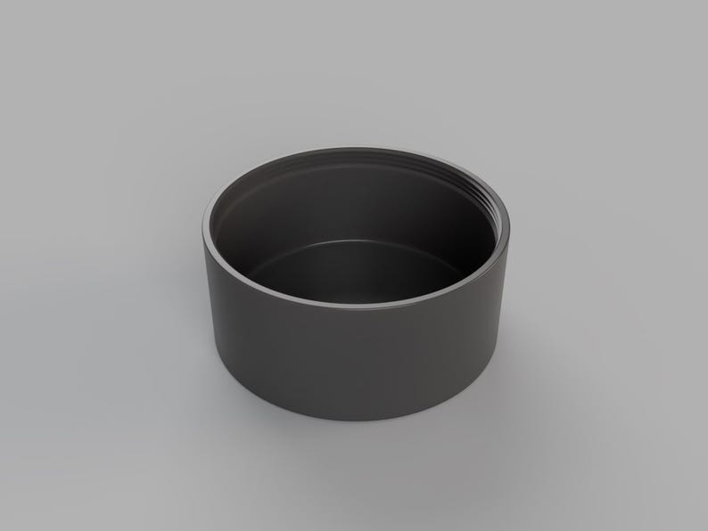 May include: A black cylindrical container with a smooth, rounded top and a slightly textured bottom.