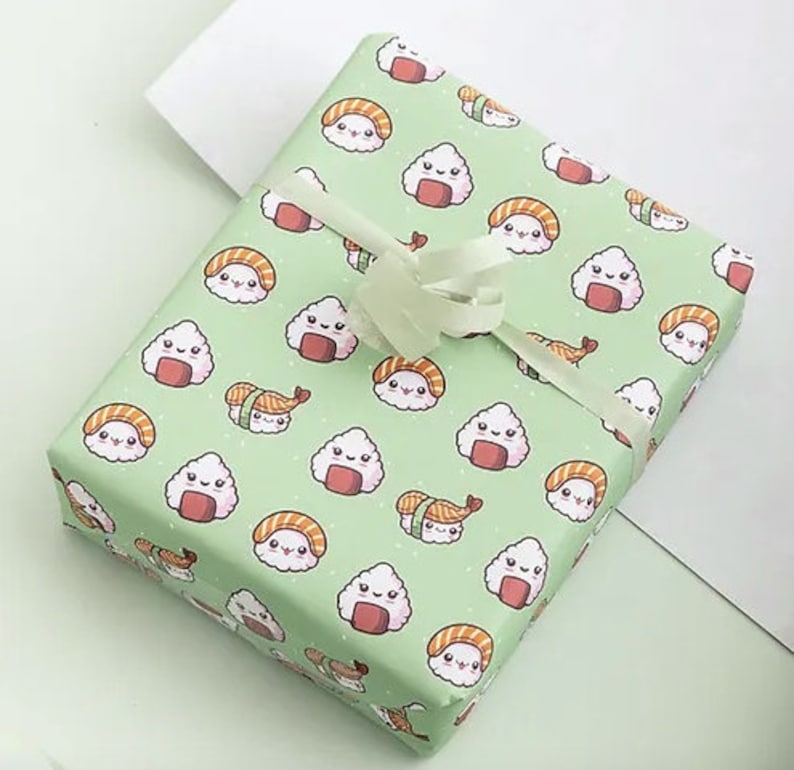 May include: A wrapped gift with light green wrapping paper featuring a repeating pattern of smiling sushi and rice ball illustrations. The gift is tied with a white ribbon and bow. The overall theme is food and gift-giving.