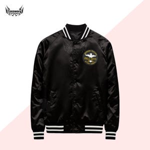 Könnte beinhalten: Schwarze Satin-Bomberjacke mit weißen Streifen an Kragen, Bündchen und Saum. Mit einem runden Aufnäher mit dem Text "MOTION PICTURE FALL GUYS STUNT ASSOC". Die Jacke hat einen Druckknopfverschluss.