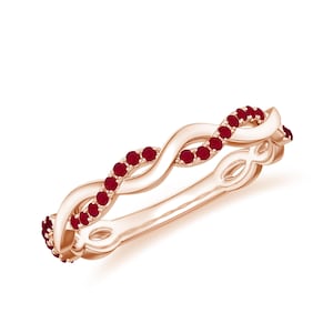 以下が含まれることがあります： ねじれたデザインのローズゴールドリング。小さくて丸い赤い宝石が飾られています。リングはインフィニティスタイルのパターンで、宝石はデザインの上部の曲線に沿ってセットされています。白い背景に設定されています。