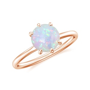 May include: A rose gold ring with a white opal gemstone set in a six-prong setting.