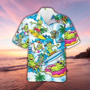 May include: Short-sleeved button-down shirt featuring a vibrant print of green aliens enjoying various beach activities. The design includes aliens surfing, parasailing, and relaxing on inflatable donuts. The shirt has a white collar and a tropical beach scene background.