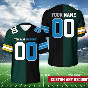 May include: A black and green football jersey with a blue and white number "00" on the front. The jersey is split down the middle with one side black and the other green. The text "TEAM NAME" is printed on the jersey. The text "YOUR NAME" is printed on the jersey. The jersey is on a green field with a white line.