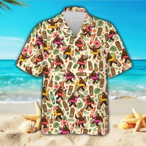 Può includere: Una camicia a maniche corte con bottoni su sfondo color crema con un motivo ripetuto di creature bigfoot marroni che indossano salvagenti colorati, intervallate da statue tiki, ananas, ukulele, tavole da surf e fiori di ibisco rosa.