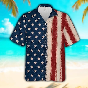 May include: A short-sleeved button-down shirt featuring a split design. The left side is navy blue with a repeating pattern of white stars, while the right side displays vertical red and white stripes with a distressed, brushstroke texture.