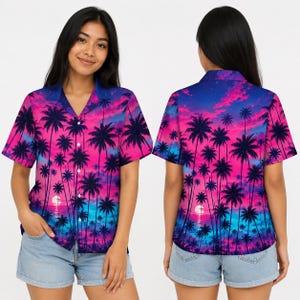 Puede incluir: Una camisa de manga corta con botones y un estampado vibrante de atardecer tropical, con siluetas de palmeras sobre un degradado de cielo en rosa brillante, morado y azul. La camisa cuenta con un cuello clásico y cierre frontal.