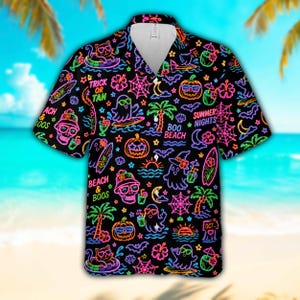 Puede incluir: Una camisa negra de manga corta con botones y un estampado de colores neón que incluye fantasmas, calabazas, gatos, palmeras, tablas de surf y flores de hibisco. El diseño incluye los textos TRICK OR TAN, BOO BEACH, BEACH & BOOS y SUMMER NIGHTS.