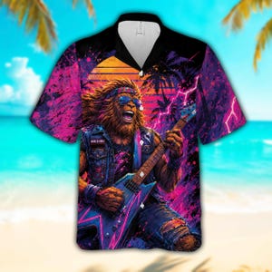 Puede incluir: Camisa de manga corta con un gráfico colorido de un Bigfoot tocando la guitarra eléctrica contra un fondo de puesta de sol. El diseño utiliza tonos rosas, morados y azules, con palmeras y rayos. La camisa tiene un cuello negro.