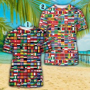 Puede incluir: Dos camisetas de manga corta, cada una cubierta con un mosaico de banderas internacionales. Las camisetas son principalmente rojas, verdes, amarillas y azules, con cuello blanco. El fondo muestra una escena de playa con palmeras y un muelle.