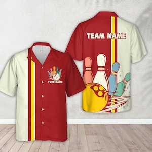 May include: Red and cream-colored bowling shirt with a bowling pin and ball graphic. The shirt has a button-down front and short sleeves. The back of the shirt has the text "TEAM NAME". The front of the shirt has the text "YOUR NAME".