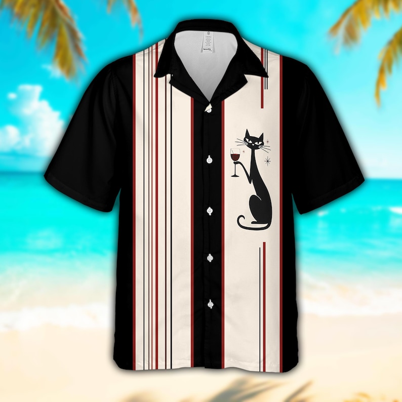 May include: A short-sleeve button-down shirt featuring a black and cream color scheme with vertical pinstripes. The front panel displays a graphic of a black cat holding a wine glass, accented by small star shapes. The shirt has a black collar.