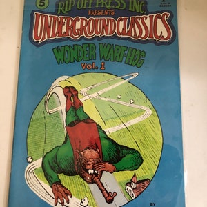 May include: A comic book cover featuring a green and red cartoon character flying through the air. The cover is blue with white text that reads "Rip Off Press Inc. Presents Underground Classics Wonder Wart Hog Vol. 1". The text at the bottom of the cover reads "By Gilbert Shelton and Tony Bell with Joe E. Brown, Jr."
