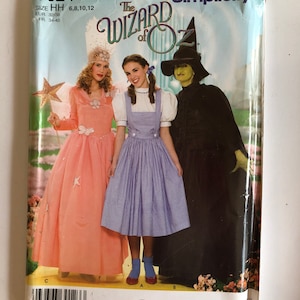 Puede incluir: Patrón de costura Simplicity número 0624 para los trajes de El Mago de Oz. El patrón incluye tres trajes: un vestido rosa con una estrella, un vestido de cuadros azules con un babero blanco y un traje de bruja verde. El patrón es para las tallas 6, 8, 10 y 12.