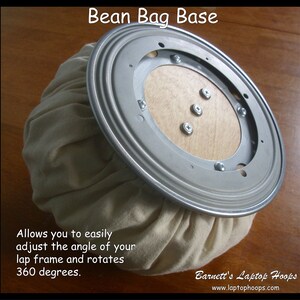 May include: A beige bean bag base with a silver swivel base. The base allows you to easily adjust the angle of your lap frame and rotates 360 degrees. "Barnett's Laptop Hoops" and "www.laptophoops.com" are printed on the base.